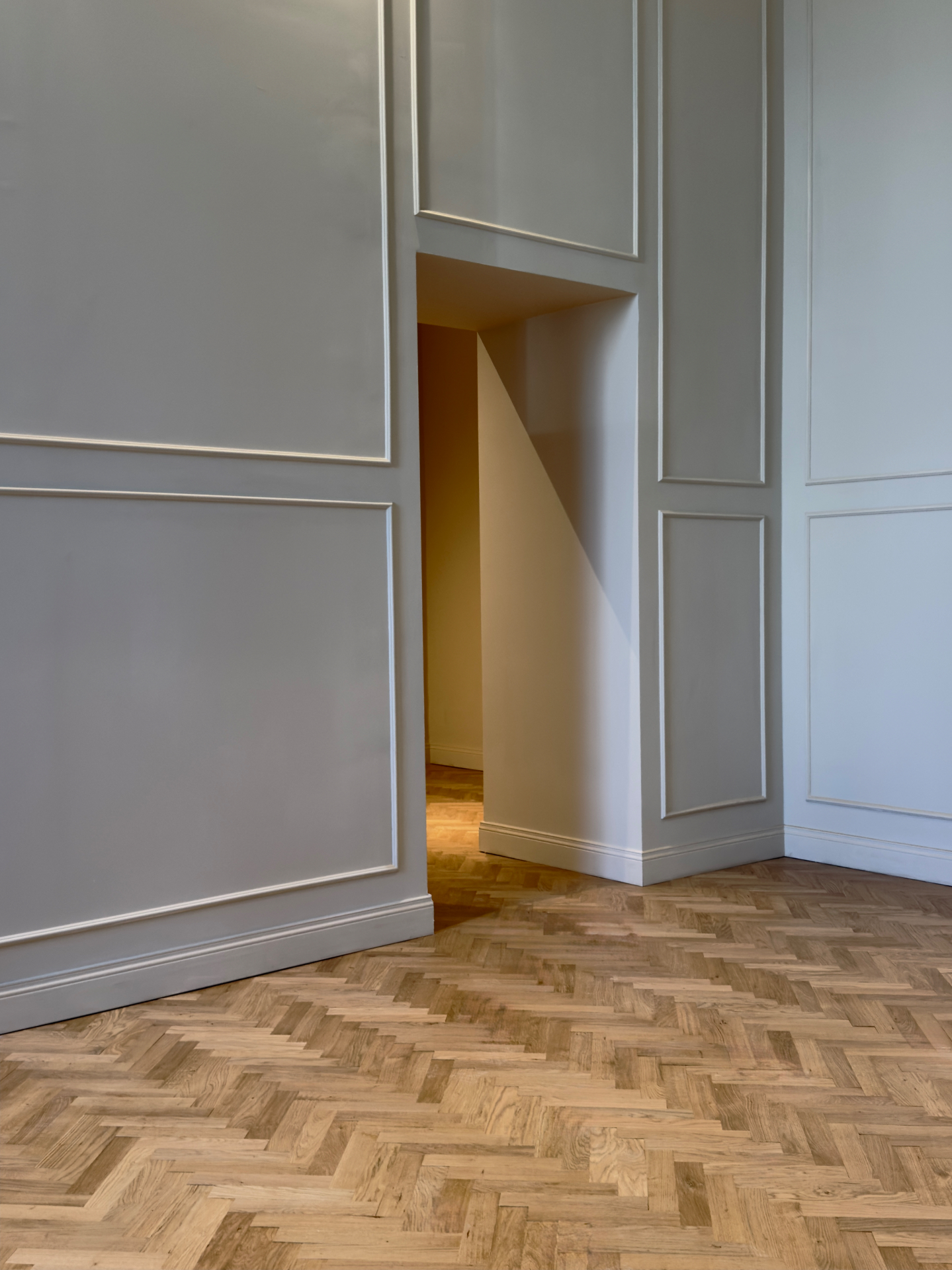Boiserie bianca con lambrecchini e pavimento in parquet a spina di pesce